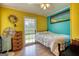 Cozy bedroom with vibrant yellow and turquoise walls, a comfortable bed, and a window offering natural light at 12621 Highway 142, Oxford, GA 30054
