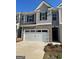 Charming townhome featuring a two-car garage, brick accents, and stylish gray siding at 1402 Grand Branch Dr, Lawrenceville, GA 30045