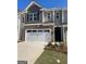 Two-story townhome featuring a stone facade, two-car garage, and neutral-toned siding at 1404 Gray Branch Dr, Lawrenceville, GA 30045
