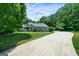 Long concrete driveway leading to a well-maintained home on a lush, green lot with a covered parking structure at 1460 Bakers Bridge Rd, Douglasville, GA 30134