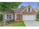 Charming stone front exterior with well-manicured lawn and attached two-car garage with bright white doors and trim at 370 Grand Teton Cir, Fayetteville, GA 30215