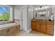 Bright bathroom showcasing soaking tub and vanity with wood cabinets and granite countertop at 55 Jolie Ln, Sharpsburg, GA 30277