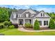 Striking two-story home featuring stone accents, white siding, black shutters, meticulously landscaped front yard and covered porch at 55 Jolie Ln, Sharpsburg, GA 30277
