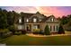 Beautiful home with illuminated landscaping at dusk, showcasing stone accents and a covered front porch at 55 Jolie Ln, Sharpsburg, GA 30277