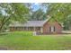 Lovely brick home with manicured lawn and black shutters nestled among mature trees on a partially cloudy day at 190 Willow Lake Ln, Sharpsburg, GA 30277