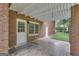 A covered patio constructed of brick, with a white pergola and doors, adjacent to a lush green yard at 190 Willow Lake Ln, Sharpsburg, GA 30277