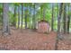Storage shed nestled among mature trees, offering practical outdoor storage in a natural setting at 190 Willow Lake Ln, Sharpsburg, GA 30277