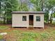 Exterior view of a small unfinished storage building with two windows, set in a wooded area at 368 Hemlock Ln, Locust Grove, GA 30248