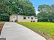 Exterior view of home with large yard, long driveway and mature trees at 368 Hemlock Ln, Locust Grove, GA 30248