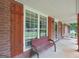 Cozy covered patio features a brick wall, wooden shutters, bench, and relaxing swing at 602 Pine Knoll Court, Mcdonough, GA 30252