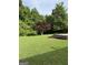 Backyard with a vibrant red maple tree, green lawn, and a partial concrete slab at 5225 Silhouette Sw Ln, Mableton, GA 30126