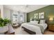 Inviting main bedroom featuring a striking green accent wall, white bedding, and well-lit ambiance at 566 Silver Moon Dr, Loganville, GA 30052