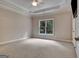This bedroom features neutral carpeting, crown moulding, and a large window with views of the trees at 115 Robinwood Ct, Fayetteville, GA 30214