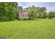 Side view of a two-story brick home surrounded by lush greenery and a well-maintained lawn at 115 Robinwood Ct, Fayetteville, GA 30214