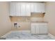 This laundry room features white cabinets, a sink, and marble floors at 115 Robinwood Ct, Fayetteville, GA 30214