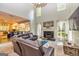 Bright living room featuring a fireplace, a ceiling fan, and an open floor plan to the kitchen at 306 Sandalin Ln, Peachtree City, GA 30269