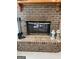 Close-up of a brick fireplace with a wooden mantel and glass doors, complete with decorative lanterns at 2142 E Atlanta Rd, Stockbridge, GA 30281