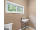 Cozy bathroom features a stylish pedestal sink and a window view of the outdoor greenery at 1385 Gordon Rd, Moreland, GA 30259