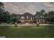 Elegant brick home at dusk, beautifully lit with manicured lawn and mature trees surrounding the property at 1385 Gordon Rd, Moreland, GA 30259