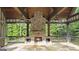 A covered outdoor fireplace with stone surround, wood beam ceiling, ceiling fans and stone flooring at 1385 Gordon Rd, Moreland, GA 30259