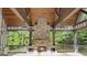A covered outdoor fireplace with stone surround, wood beam ceiling, ceiling fans and stone flooring at 1385 Gordon Rd, Moreland, GA 30259