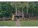 Charming backyard playground with a slide, climbing net, and playhouse amid serene greenery at 1385 Gordon Rd, Moreland, GA 30259