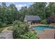 Aerial view of a backyard pool, spa, and pool house surrounded by lush landscaping and mature trees at 1385 Gordon Rd, Moreland, GA 30259