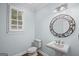 Bright powder room featuring a pedestal sink, decorative mirror, and window with plantation shutters at 1385 Gordon Rd, Moreland, GA 30259