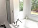 Spa-like bathroom featuring a soaking tub, glass shower, and a view of the backyard at 130 Victoria Pl, Fayetteville, GA 30214