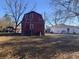 Exterior shot of the red barn style home with a ladder and outbuildings in the back at 10142 Washington Street, Covington, GA 30014