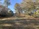 The flat and spacious backyard surrounded by mature trees and foliage, with the lawn covered in leaves at 10142 Washington Street, Covington, GA 30014