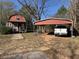 The home has a red exterior, a small porch, and a covered carport with a white truck at 10142 Washington Street, Covington, GA 30014