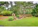 Picturesque backyard featuring a fire pit, lush green lawn, mature trees, and a charming shed for storage or hobbies at 55 Ashton Pl, Covington, GA 30016