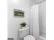 Bathroom showing the toilet and shower/bath with white tile, blue floral shower curtain and artwork at 654 Cannon Rd, Sharpsburg, GA 30277