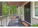 Inviting front porch with a bench and a welcome mat, surrounded by a lush forest at 654 Cannon Rd, Sharpsburg, GA 30277