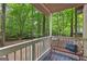 Cozy covered porch with a vintage metal bench overlooking serene wooded views at 654 Cannon Rd, Sharpsburg, GA 30277