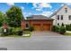 A brick two-car garage with wooden doors surrounded by lush green landscaping and a blue sky at 185 Central Ave, Fayetteville, GA 30214