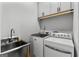 Well-lit laundry area features a stainless steel utility sink, washer, dryer and upper cabinets at 185 Central Ave, Fayetteville, GA 30214