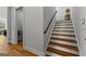 Bright interior staircase with wood treads, white risers, and black handrail near an entrance and hardwood floors at 185 Central Ave, Fayetteville, GA 30214