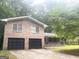 Brick home featuring a two-car garage and a welcoming covered porch, surrounded by mature trees at 345 Fond Du Lac Dr, Stone Mountain, GA 30088
