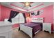 A pink bedroom features a white bed with a purple comforter and modern décor at 1028 Gloria Grand Blvd, Mcdonough, GA 30252