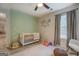 Well-lit Bedroom with a white crib, play mat, and pale green accent wall at 527 Malcom Rd, Covington, GA 30014