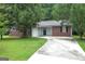 Charming brick home featuring a paved driveway, lush lawn and mature shade trees enhancing curb appeal at 2039 Faith Cv, Atlanta, GA 30349