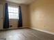 This bedroom offers natural light from a large window and modern, gray wood-look flooring at 5793 Springfield Pl, Ellenwood, GA 30294