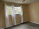 This bedroom offers natural light from a large window and modern, gray wood-look flooring at 5793 Springfield Pl, Ellenwood, GA 30294