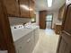 Well-equipped laundry room with washer, dryer, wooden cabinetry, and patterned wallpaper at 370 Rosetta Nw Ln, Conyers, GA 30012