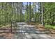 Gated gravel driveway winding through a serene wooded landscape leading to the property at 211 Beavers Rd, Grantville, GA 30220