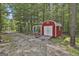 Red storage shed with white trim, providing ample outdoor storage space amidst a serene wooded setting at 211 Beavers Rd, Grantville, GA 30220