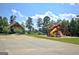 Community playground with a slide and swings surrounded by mature trees and green space at 30 Dorset Ct, Sharpsburg, GA 30277