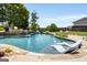 A luxurious pool with integrated lounge chairs and a stone waterfall, surrounded by lush landscaping at 30 Dorset Ct, Sharpsburg, GA 30277
